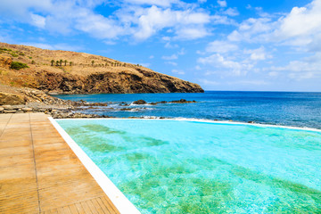 Infinity swimming pool on volcanic coast of Madeira island, Portugal