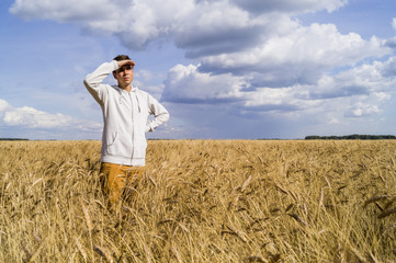 Naklejka na ściany i meble A man in a field of wheat looks to the future