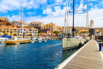 Sailing boats in port with colourful houses near Canical town on coast of Madeira island, Portugal
