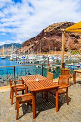 Restaurant table on terrace in sailing port on coast of Madeira island, Portugal