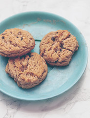 Closeup of crunchy chocolate chip cookies or biscuits on a decorative plate on marble background