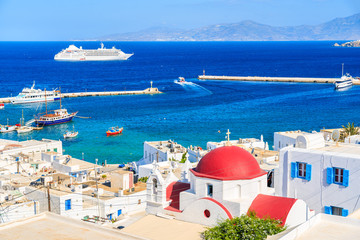 Typical Greek white church with red dome and view of Mykonos port, Mykonos island, Cyclades, Greece © pkazmierczak