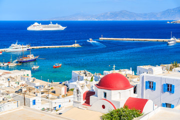 Typical Greek white church with red dome and view of Mykonos port, Mykonos island, Cyclades, Greece