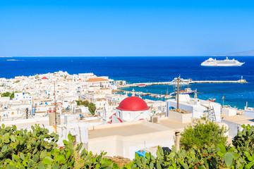 Green cacti plants in foreground and typical Greek white church with red dome in Mykonos port, Mykonos island, Cyclades, Greece © pkazmierczak