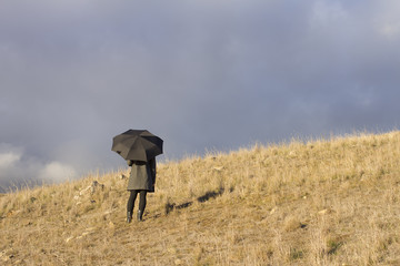 Person Standing in Field Holding Umbrella