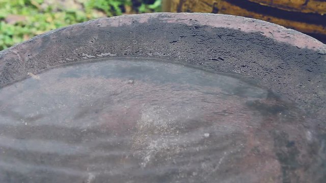Raindrop falling to bottom of big earthen jar