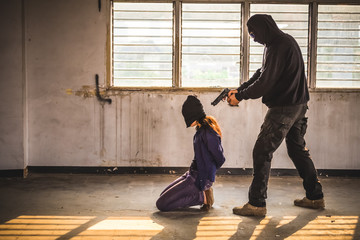 A terrorist man holding gun kidnapping young women for a hostage in abandoned building. Rape, terrorism, crime, violence, robbery and killer of women conception.