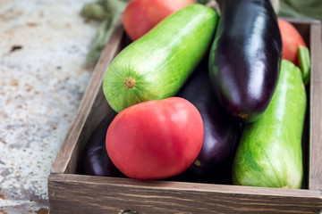 Ingredients for ratatouille or vegetable dish: eggplants, zucchini and tomato in a wooden box,...