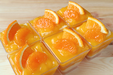 Fototapeta na wymiar Rowed up Mandarin Orange Cakes Topped with Fresh Oranges in Glass Bowls 