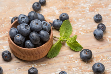 Black ripe berries lie on a wooden saucer and scattered on an old board