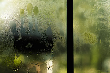Handprint behind the window, selective focus on drop water and surface on glass. Scream for help, halloween day, depression, stress, panic concept.