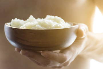 A young man holding a wooden bowl of rice porridge. The concept of a healthy Breakfast.