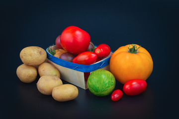 Assortment organic vegetable colorful tomatoes and potatoes on black background