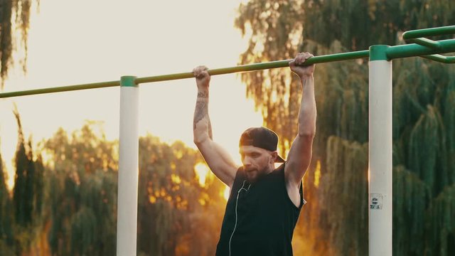young man pulls himself up on a bar in the park