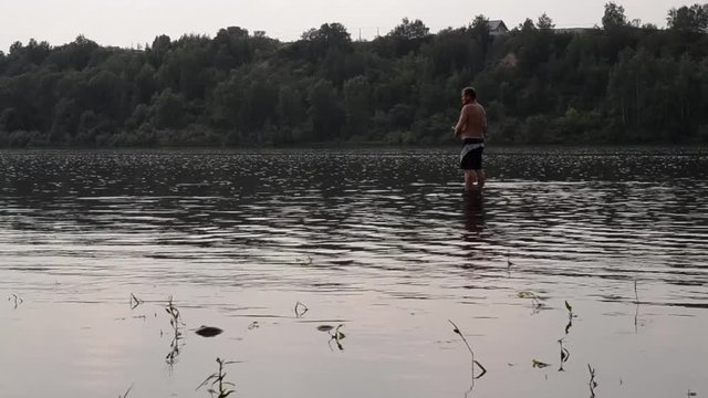 half-naked fisherman with a fishing rod fishing in the calm river