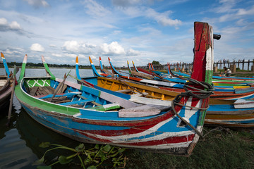 Fototapeta na wymiar Traditional painted boats at U Bein Bridge at Taungthaman Lake, Mandalay, Myanmar