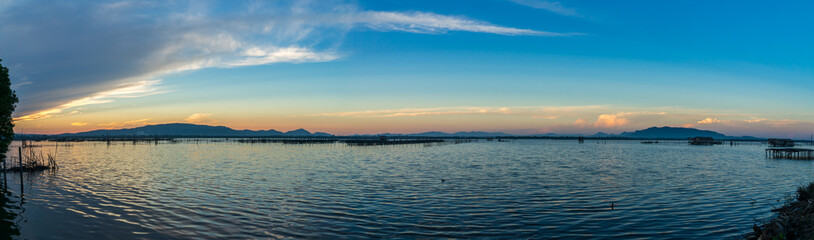 Fototapeta na wymiar Panorama photo of beatiful twiligh sky over Songkhla lake with blue cloudy sky and mountain in background.