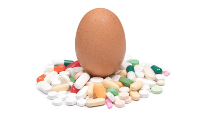 Brown chicken egg on variety pills and capsules. Isolated on white background.