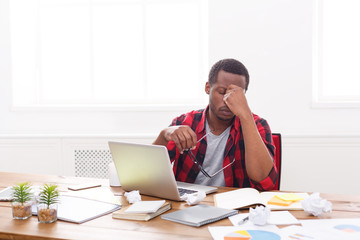 Tired black businessman in office, work with laptop