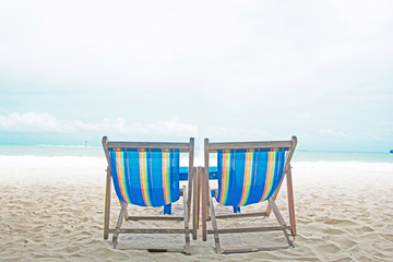 Nylon wooden chairs on the white sand beach with blue sea in Thailand.