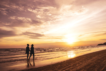 Fototapeta na wymiar Couple Walking by the Ocean Shoreline