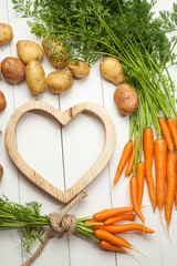 Brown heart shape plate with Fresh organic Vegetables on Wooden table. Healthy Vegetarian food, View from above.