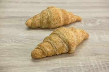 CROISSANT
Two brown croissant on the wood table.