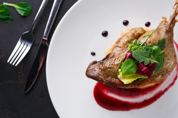 Restaurant meals. Duck confit with vegetables on black background