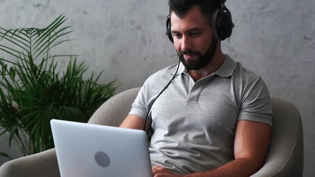 Positive bearded man working on the laptop