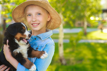 Little girl with a berner sennenhund puppy, outdoor, summer