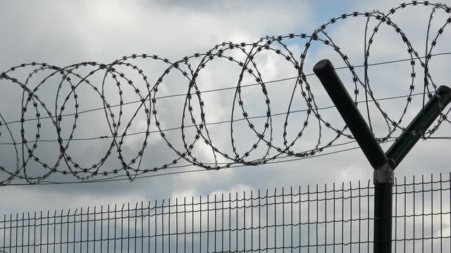 Security fence with a barbed wire with grey sky. Fence with a barbed wire.