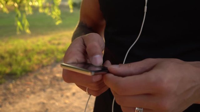 Man browses the playlist on his player before jogging, close-up