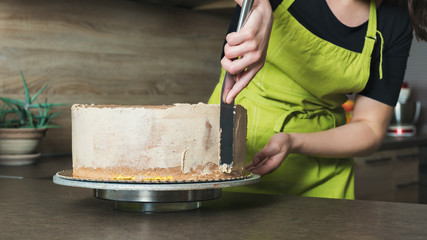 Unrecognisable woman decorating a delicious layered sponge cake with chocolate icing cream © andreaobzerova