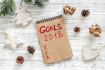 Make a goals list for 2018. Notebook and christmas decoration on wooden background top view   