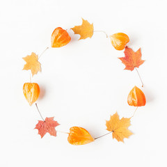Fototapeta na wymiar Autumn composition. Wreath made of autumn maple leaves and physalis flowers. Flat lay, top view, copy space