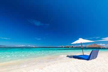 Naklejka premium Beautiful beach. Sunbeds with umbrella on the sandy beach near the sea. Summer holiday and vacation concept. Inspirational tropical beach.