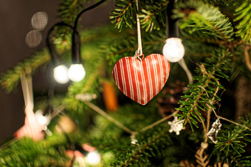 Christmas tree decoration. Lights on Christmas tree. Heart pendant on christmas tree.