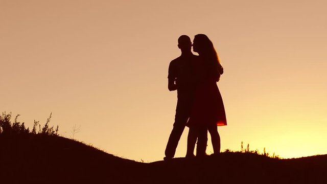 Couple in love dancing silhouette at sunset nature and kissing. Loving man and woman with dog dancing silhouette slow motion video