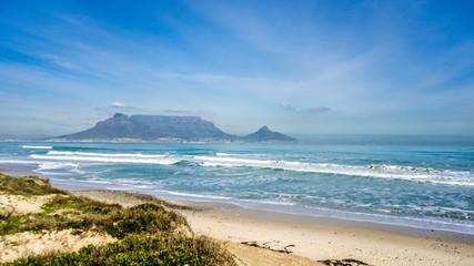 Fototapeta na wymiar Early morning view of Cape Town and Table Mountain with Lion's Head and Signal Hill on the right and Devil's Peak on the left. Viewed from Bloubergstrand just north of the city