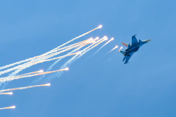 Aircraft fighter flies and shoots heat guns in the blue sky...