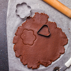 The process of baking chocolate cake base of shortcrust pastry. Working with dough at home kitchen. Ingredients for baking: eggs, flour, butter, sugar on black table and dark background.