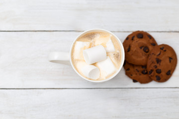 Latte with marshmallow and chocolate cookies on a white wooden background;
