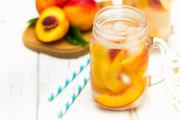 Homemade iced lemonade with ripe peaches. Fresh peach ice tea in a mason jar.