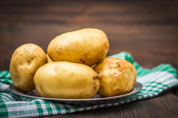 Raw potatoes on a brown wooden background