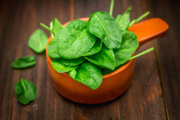 Fresh juicy spinach leaves on a wooden brown table. Natural products, greens, healthy food, vitamins.