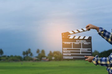 Kid playing film clapper board against summer sky background. Film director concept.