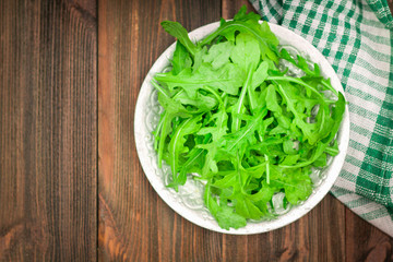 Fresh juicy leaves of arugula on a brown wooden table.