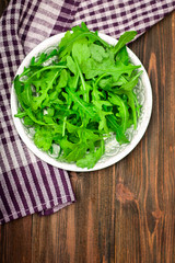 Fresh juicy leaves of arugula on a brown wooden table.