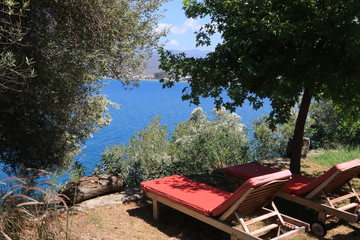 Sunbeds with with a great view looking through trees onto the bays at fethiye in turkey, 2017