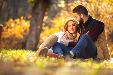 Fototapeta premium Love couple sitting under a tree in the colorful spring garden at sunset